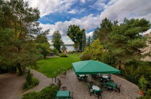 einen Blick über eine Terrasse mit einem grünen Sonnenschirm in der Unterkunft Hotel Seeschlösschen in Groß Köris