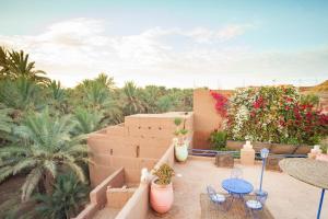 une terrasse avec des tables et des chaises ainsi qu'une haie fleurie. dans l'établissement La Petite Kasbah, à Zagora