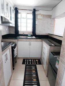 a small kitchen with black and white cabinets and a window at Cosmic home in Thika