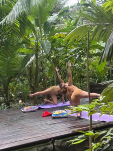 two women doing yoga on a wooden deck at REFUGIO DO SAGRADO MORERE Tropical Lodge - A Casa do Vigía in Moreré