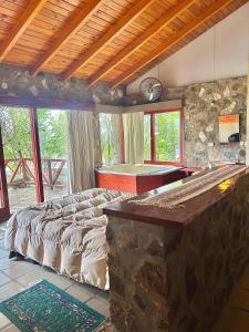 a bedroom with a bed and a stone wall at Cabaña julian in La Cumbrecita