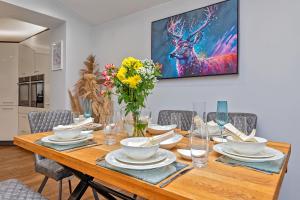a dining room table with chairs and a painting on the wall at CONTRACTOR FRIENDLY-Large Driveway-THREE SMART TV's-Central Location-FOUR DOUBLE BEDROOMS in Luton