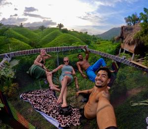 a group of people laying on a hammock in the grass at The Valley Tayrona hostel- A social jungle hostel in El Zaino