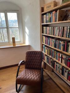 a chair in front of a book shelf with books at Schloss1611 B&B in Erbendorf