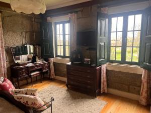 a living room with a tv and a dresser and windows at Casa da Costinha in Cinfães