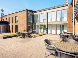 a patio with tables and chairs in front of a building at Apartment with shared kitchen in Vedersø in Ulfborg