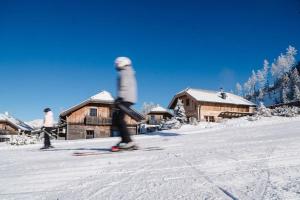 a person on skis in the snow in front of buildings at Almdorf Katschberg in Katschberghöhe