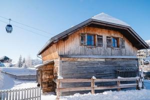 a wooden cabin in the snow with a window at Almchalet am Katschberg in Katschberghöhe