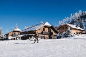 a man standing in the snow in front of a lodge at Almchalet am Katschberg in Katschberghöhe