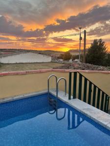 a swimming pool with a sunset in the background at La Huerta del Rodeo in Navas de San Antonio