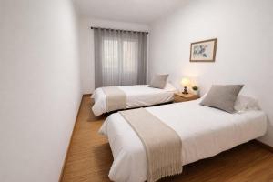 two beds in a room with white walls and wood floors at Casa do Paraíso in Elvas