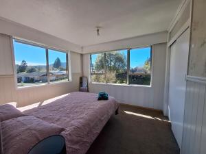 a bedroom with a bed and two large windows at All decked out in Rotorua