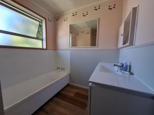 a bathroom with a sink and a tub and a mirror at All decked out in Rotorua +9 photos
