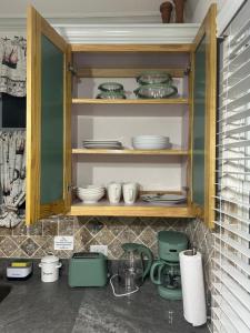 a cabinet filled with plates and dishes in a kitchen at Windy Nook - The Contemporary Tiny Home in Saint Philip +22 photos