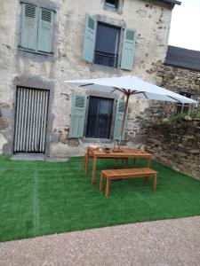 a picnic table and an umbrella in front of a building at Maison 4 à 9 personnes à la campagne in Alleuze