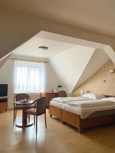 a bedroom with a large bed and a table at Hotel U Labutě in Žďár nad Sázavou