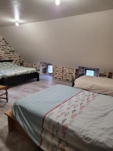 a bedroom with two beds and a stone wall at Maison 4 à 9 personnes à la campagne in Alleuze +4 photos