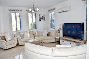 a living room with white furniture and a flat screen tv at Latchi Beach Front Villa - Private Heated Pool - Amazing Uninterrupted Sea Views in Polis Chrysochous