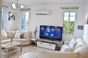 a living room with white furniture and a flat screen tv at Latchi Beach Front Villa - Private Heated Pool - Amazing Uninterrupted Sea Views in Polis Chrysochous