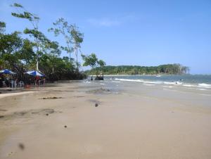 an empty beach with people and the ocean at Suite das Mangueiras I in Soure