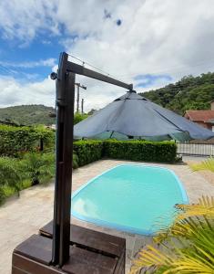 a umbrella over a swimming pool in a yard at Recanto Romig in Pomerode