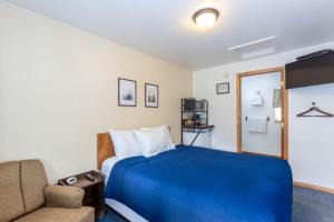 a hotel room with a blue bed and a chair at Cascade Motel in Oakridge