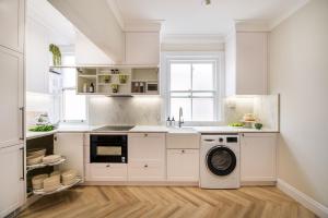 a kitchen with white cabinets and a dishwasher at Manly Waterfront Apartment Harbourside in Sydney