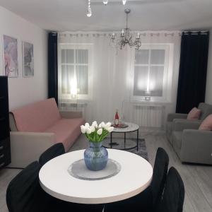 a living room with a vase of flowers on a table at Apartament z kominkiem RetroGlam in Mieroszów