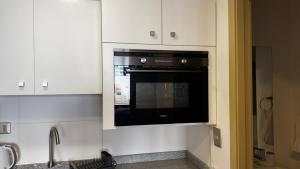 a black microwave in a kitchen with white cabinets at Estudio Moderno Equipado - Centro Concepción, a pasos de la Estación in Concepción