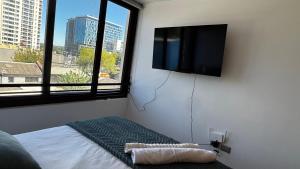 a bedroom with a flat screen tv and a bed at Estudio Moderno Equipado - Centro Concepción, a pasos de la Estación in Concepción