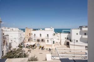 a group of white buildings with the ocean in the background at Old tuff apartments in Polignano a Mare