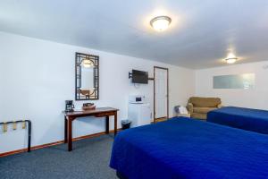 a hotel room with two beds and a television at Cascade Motel in Oakridge