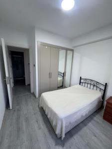 a bedroom with a white bed and a mirror at Joy Residence- 3 bedroom apartment with balcony in Nicosia