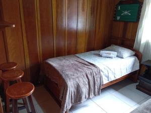 a bedroom with a bed with wooden walls and two stools at Casa Recanto do Sossego in Antonina