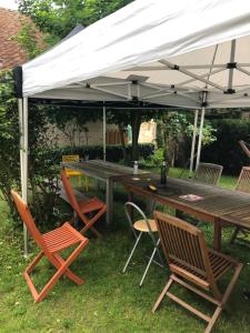 a wooden table and chairs under a white canopy at COMME chez VOUS in Saint-Satur