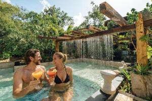 a man and woman drinking cocktails in a swimming pool at ARKA Tulum in Tulum