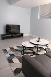 a living room with two tables and a flat screen tv at Modern 2BR Basement Suite Private Entrance in Brampton
