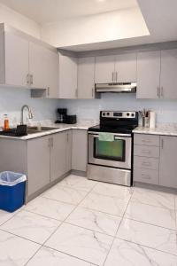 a kitchen with white cabinets and a stainless steel oven at Modern 2BR Basement Suite Private Entrance in Brampton
