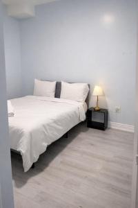 a bedroom with a bed with white sheets and a lamp at Modern 2BR Basement Suite Private Entrance in Brampton