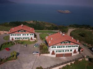 an aerial view of two large white houses with the ocean at Hotel Spa Gametxo in Ibarrangelu