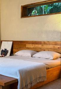 a bed with a wooden headboard and a window at Dalakit House Hidden Garden Oasis in Lambojon