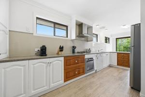 a kitchen with white cabinets and a large window at Dixon Delight in Inverloch