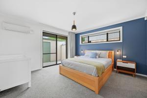 a blue bedroom with a bed and a window at Dixon Delight in Inverloch