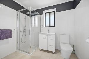 a white bathroom with a shower and a toilet at Dixon Delight in Inverloch +4 photos