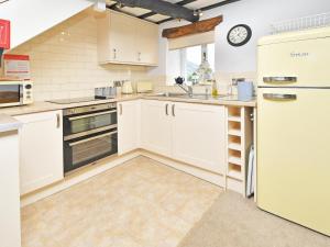 a kitchen with white cabinets and a refrigerator at Osprey Cottage in Bassenthwaite +20 photos