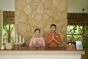 Ein Mann und eine Frau stehen vor einem Tresen. in der Unterkunft Reset Lombok Hotel in Kuta Lombok