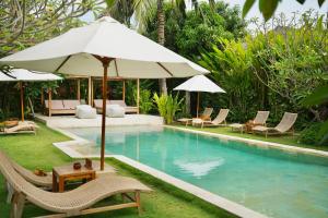 ein Pool mit Stühlen, einem Sonnenschirm und einem Tisch in der Unterkunft Reset Lombok Hotel in Kuta Lombok