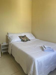 a bedroom with a white bed with towels on it at Lar doce lar! in Divinópolis +4 photos