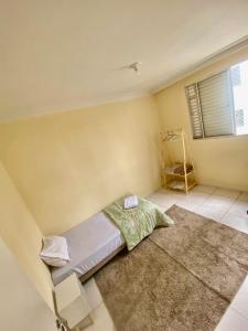 a small bedroom with a bed and a rug at Lar doce lar! in Divinópolis