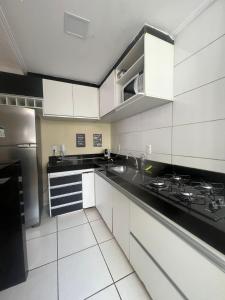 a kitchen with white cabinets and black counter tops at Lar doce lar! in Divinópolis